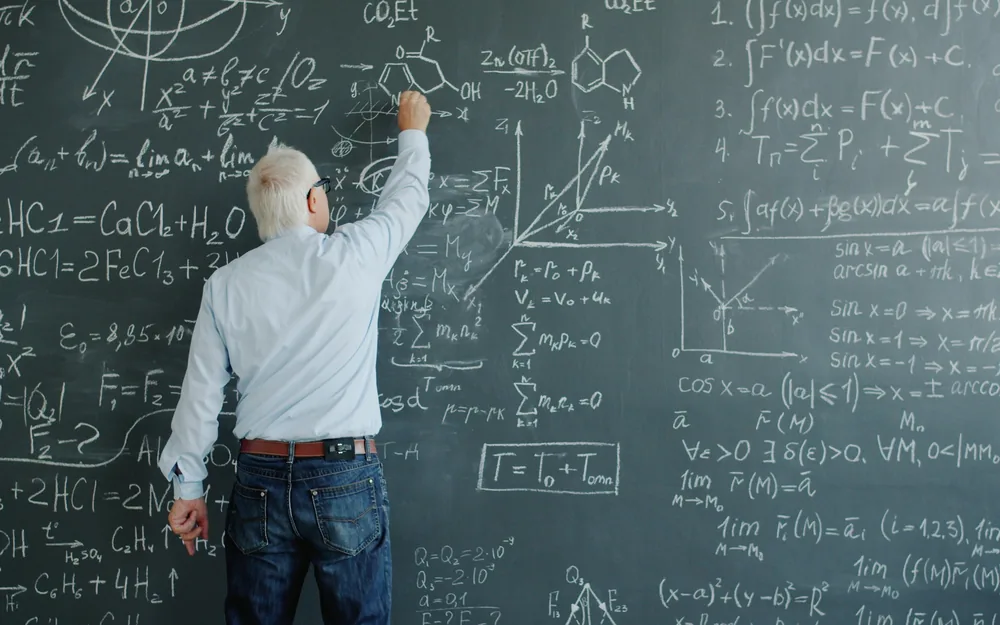 Professor working through equations on a chalkboard