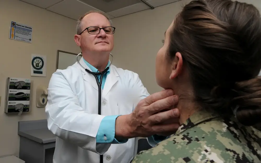 Physician examining a service member in a federal clinic